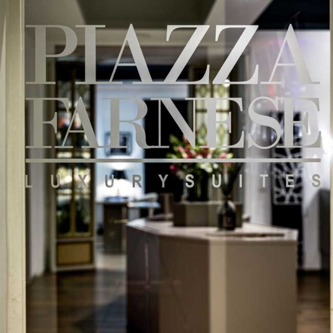 Ingresso di Piazza Farnese Luxury Suites con logo inciso sulla vetrata